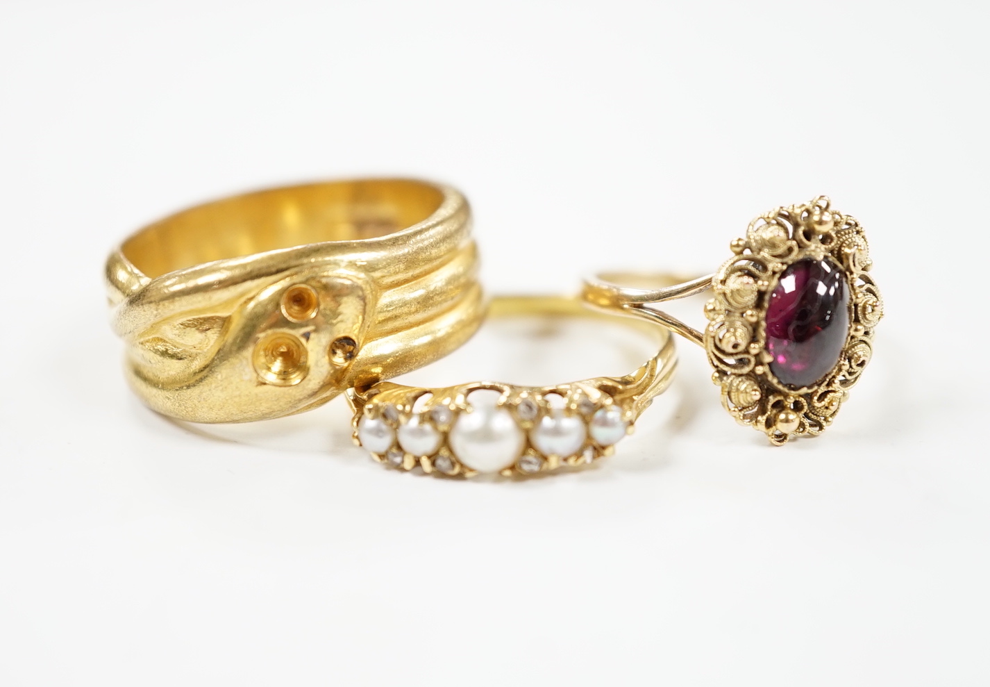 A yellow metal and cabochon garnet set ring, an Edwardian 18ct and graduated split pearl set half hoop ring, with diamond chip spacers and one other ring.